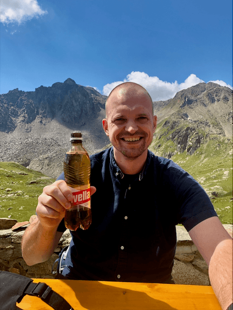 Richard Bergsma smiling in the mountains of Switzerland holding Revella